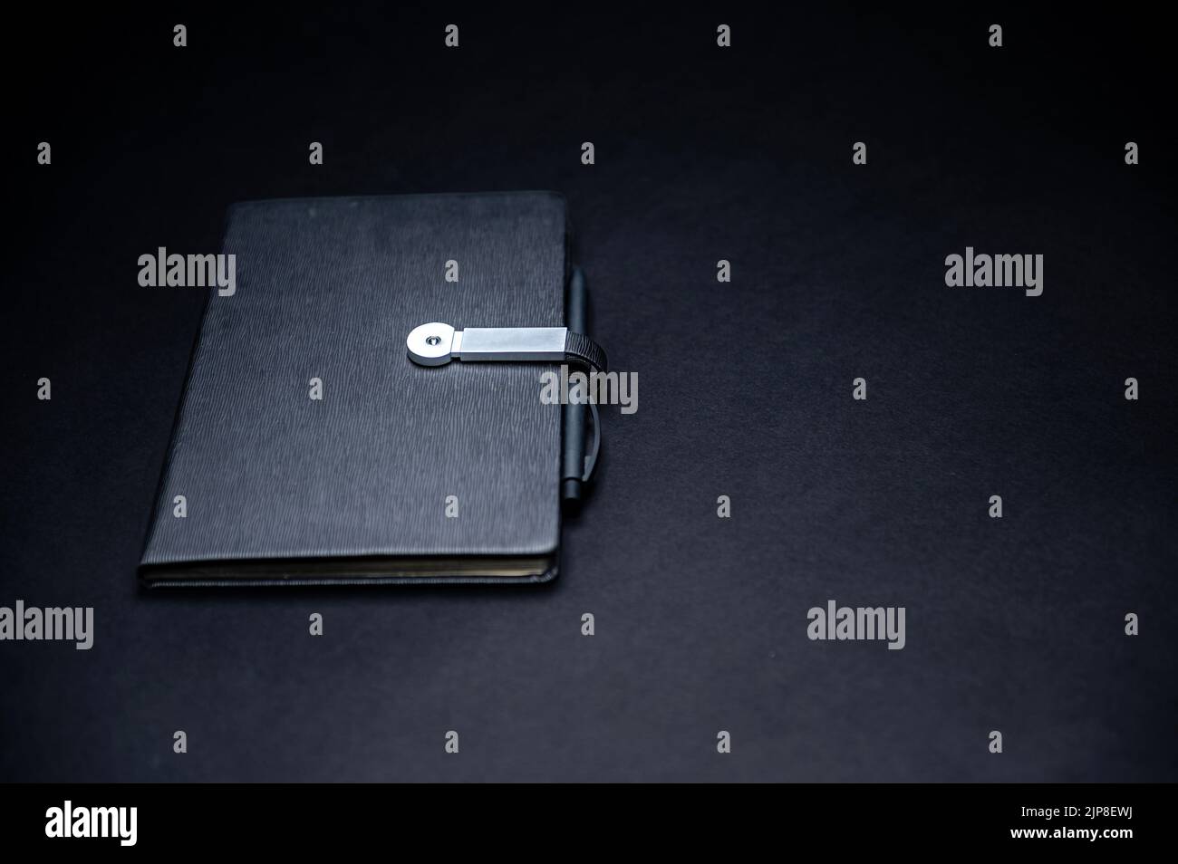 Schwarzer Planer oder Notizbuch mit isoliertem Stift auf schwarzem Hintergrund, Modell, Kopierbereich, Nahaufnahme Stockfoto