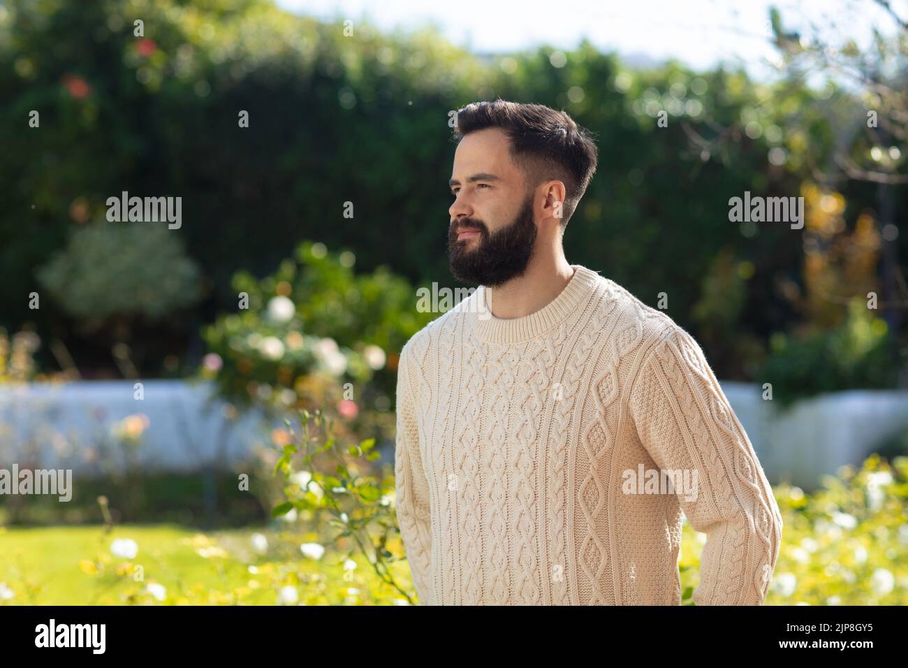 Glücklicher kaukasischer Mann mit lächelndem Bart, der im Garten steht Stockfoto