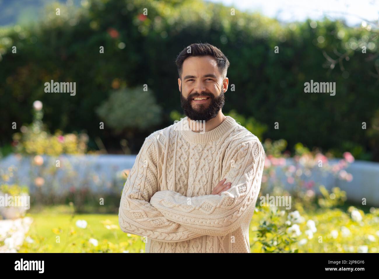 Porträt eines glücklichen kaukasischen Mannes mit lächelndem Bart im Garten Stockfoto