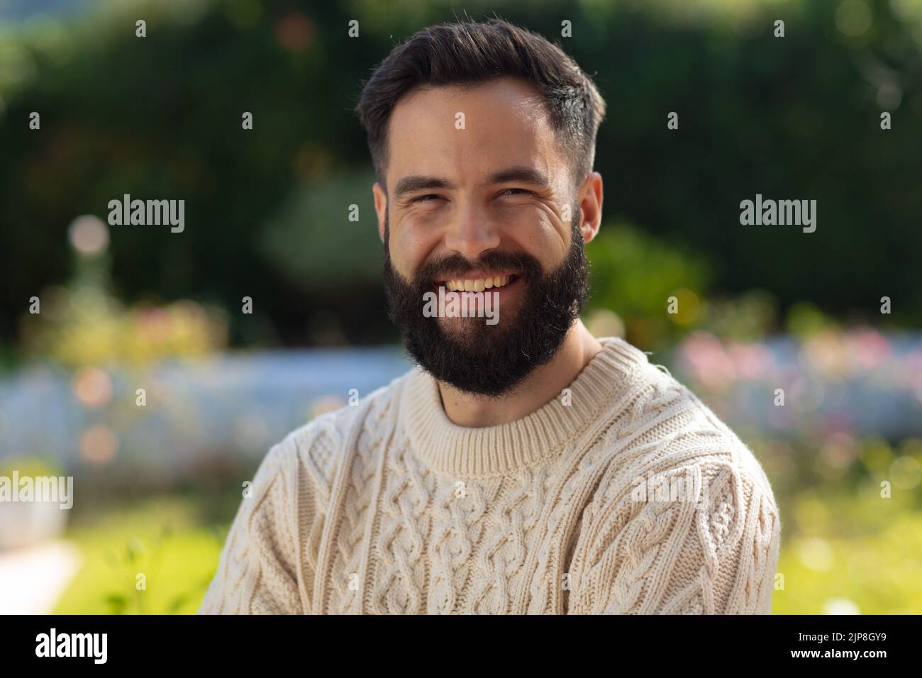 Porträt eines glücklichen kaukasischen Mannes mit lächelndem Bart im Garten Stockfoto