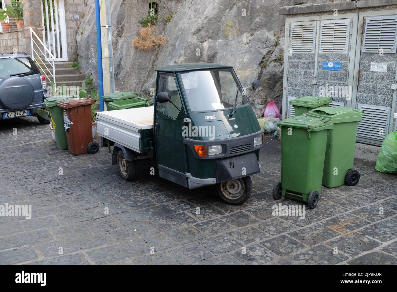 Ein leichtes Nutzfahrzeug aus dem Jahr Ape50, hergestellt vom italienischen Kraftfahrzeughersteller Piaggio, das in Sorrent (Italien) unter Abfallbehältern geparkt ist. Stockfoto