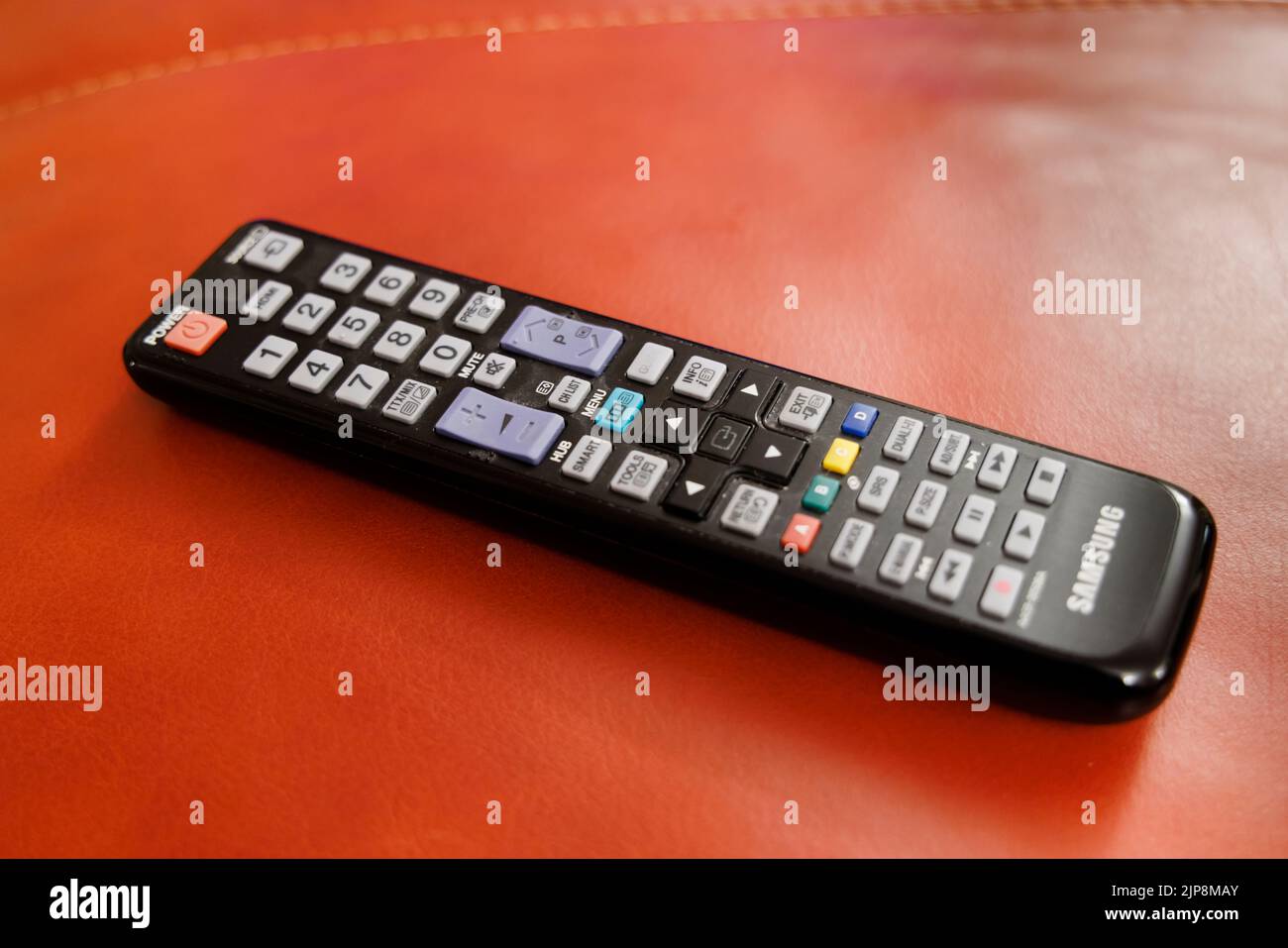 Ein gebrauchter schwarzer Samsung Fernseher Fernbedienung Hörer vor einem roten Hintergrund Stockfoto