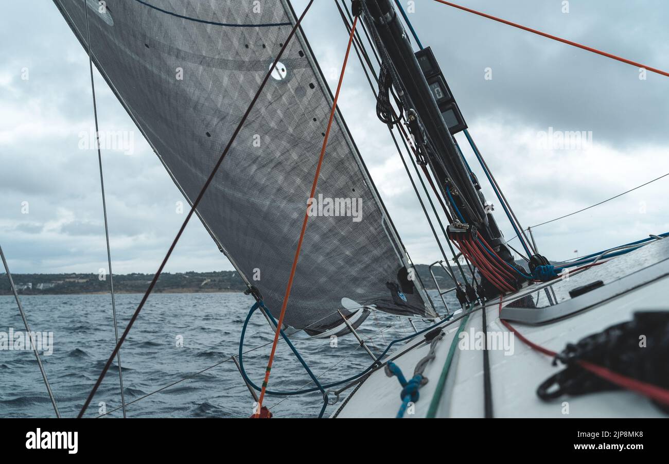 Segelyacht im Meer. Nahaufnahme von Deck, Mast und Segeln mit bewölktem Himmel. Stockfoto