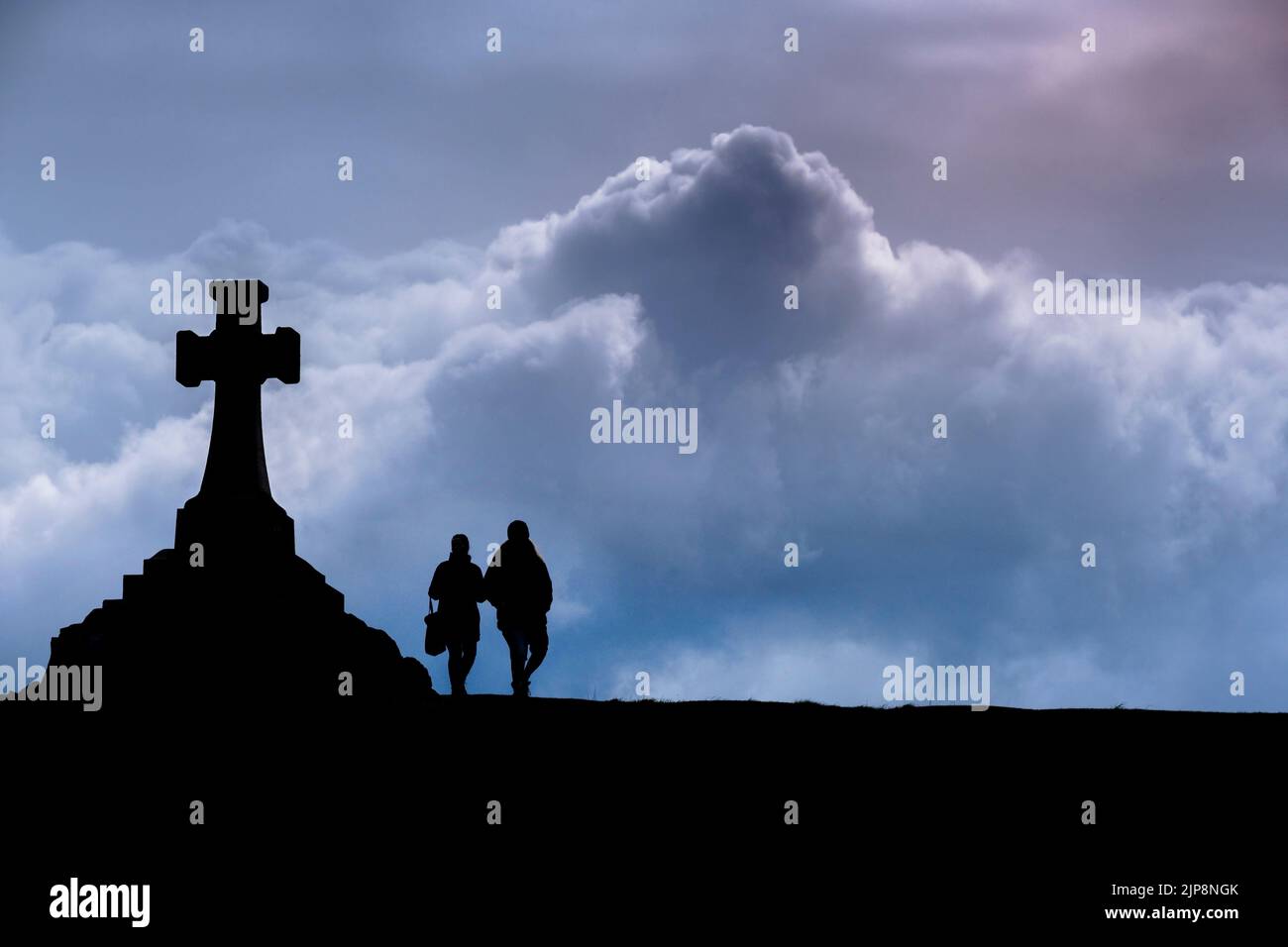 Die Silhouette eines Paares, das am großen war Memorial Cross in Newquay in Cornwall im Vereinigten Königreich vorbeigeht. Stockfoto