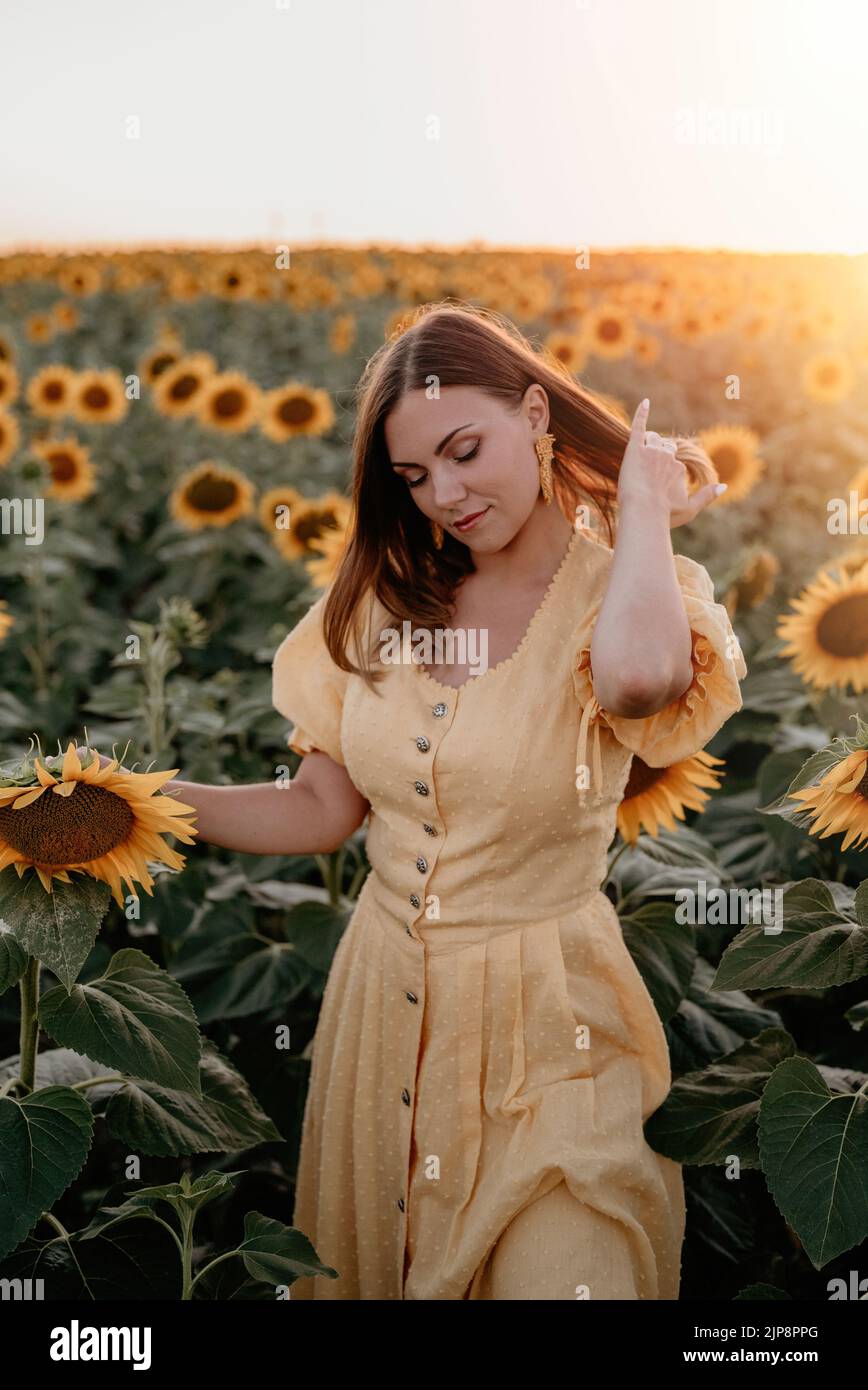 Hübsche Frau im Retro-Kleid posiert in Sonnenblumen Feld. Gelbe Farben, warme Tonung. Vintage zeitlose Mode, erstaunliche Abenteuer, Land, ländlich Stockfoto