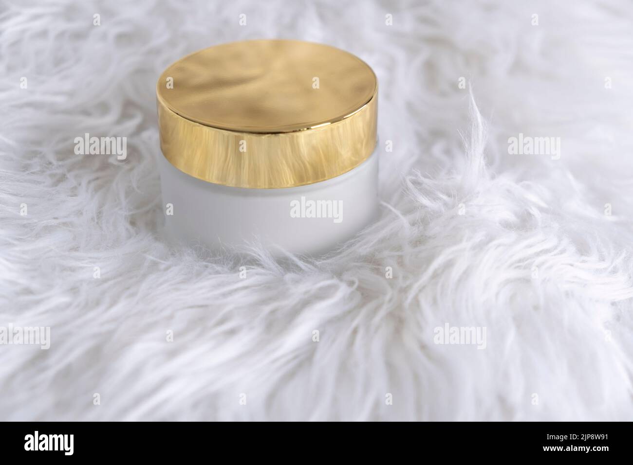 Ein weißes Glas für feuchtigkeitsspendende Creme mit einem goldenen Deckel auf weißem Hintergrund. Modell für die Markenverpackung von Produkten. Hochwertige Fotos Stockfoto