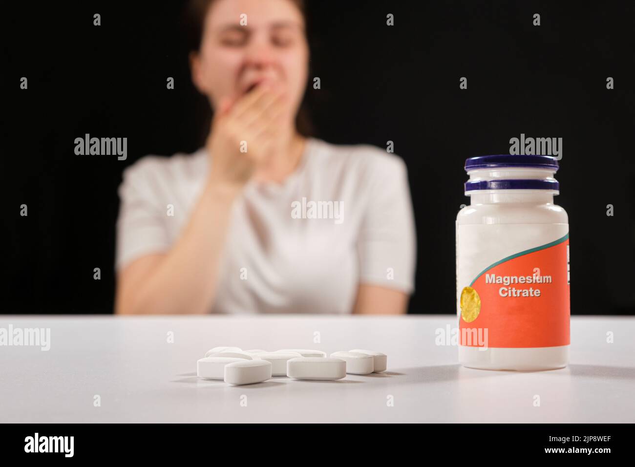 Eine müde Frau und ein Glas Magnesiumcitrat. Nahrungsergänzungsmittel gegen Müdigkeit, Reizbarkeit und Schlaflosigkeit Stockfoto