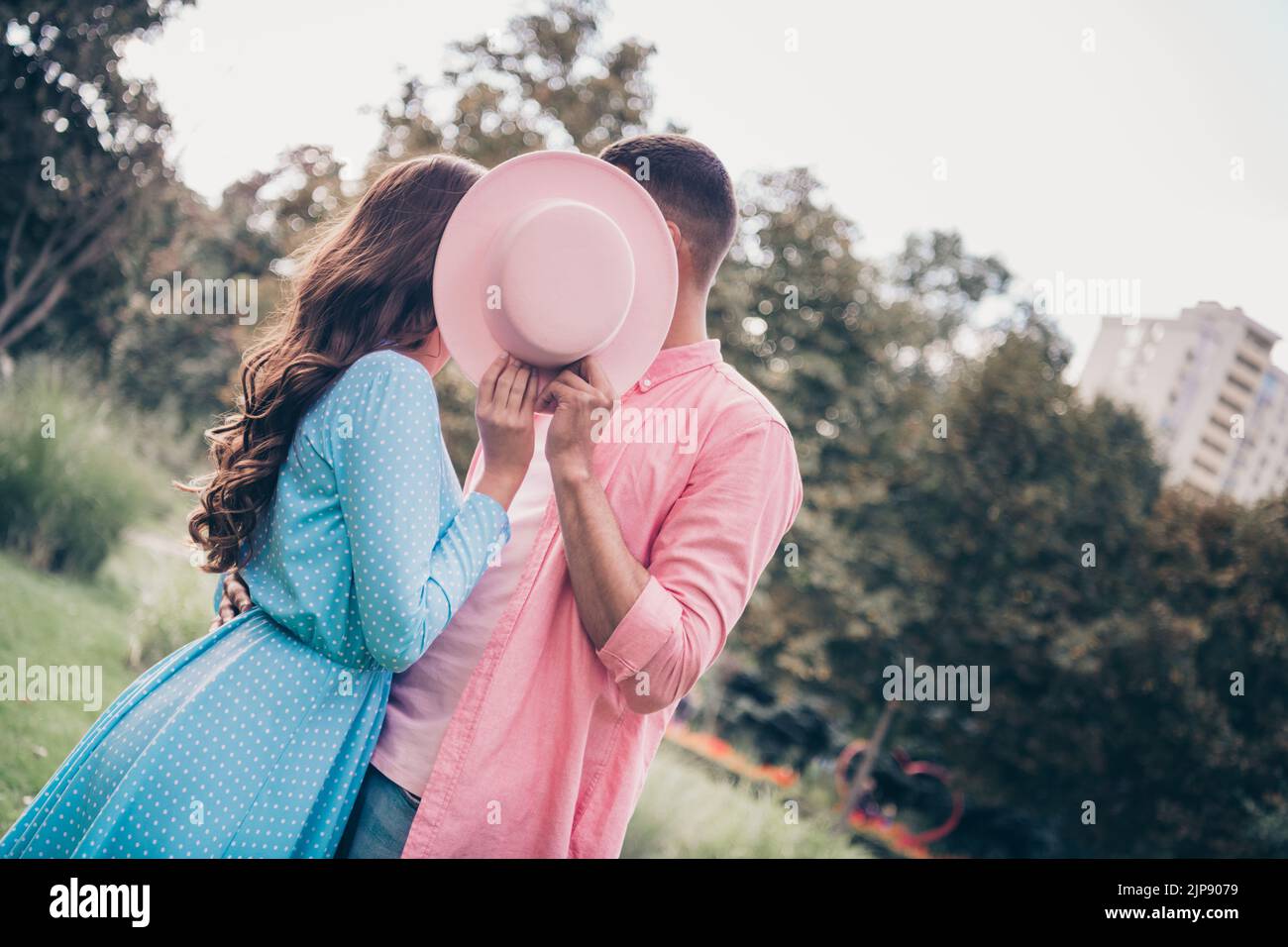 Nahaufnahme Foto-Session von zwei jungen Studenten Freund Freundin versteckt küssen Abdeckung rosa Hut tragen stilvolle Kleidung im Park Stockfoto