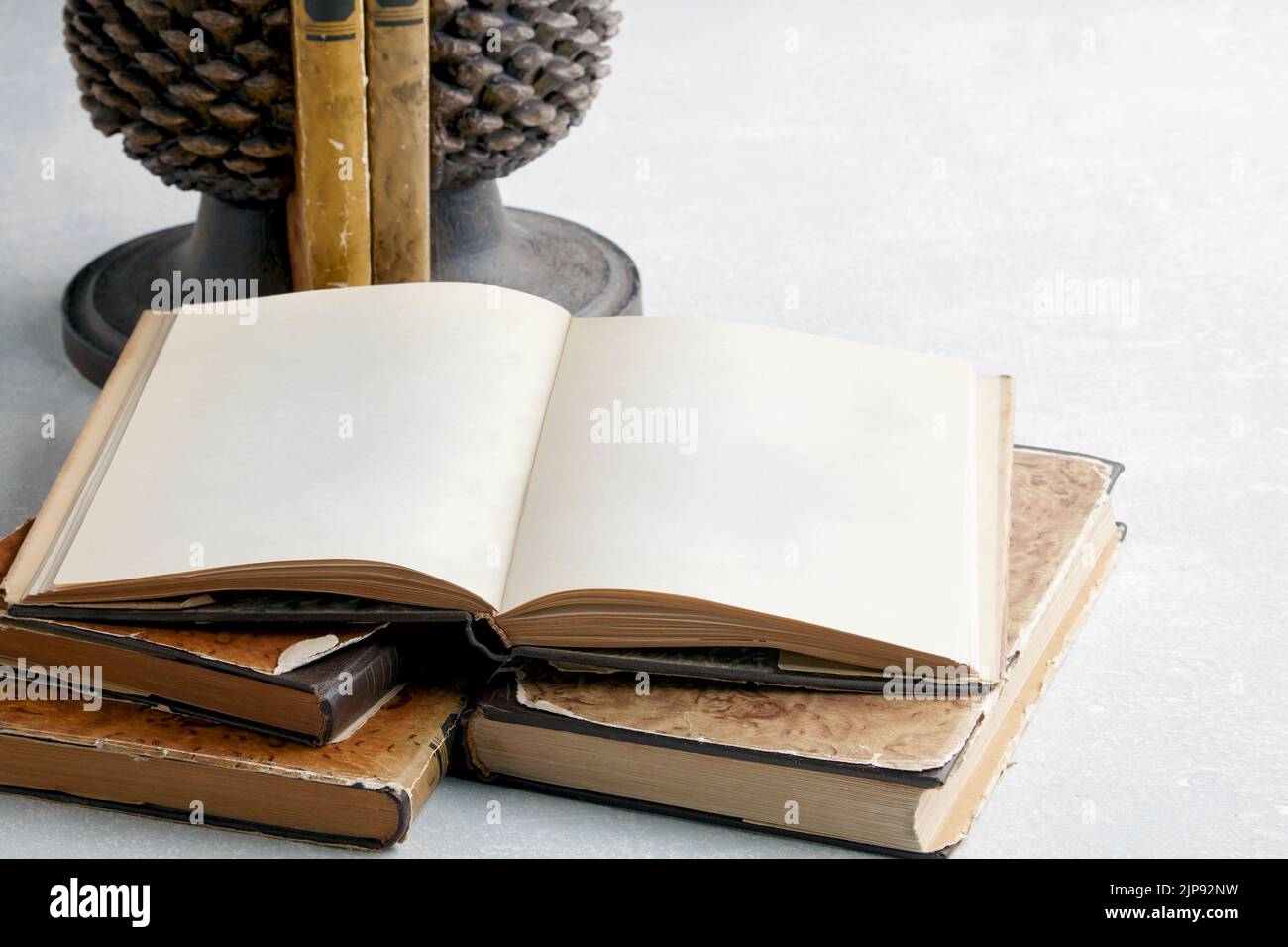Ein offenes VintageBuch mit leeren Seiten auf einem Stapel alter schäbiger Bücher und einem