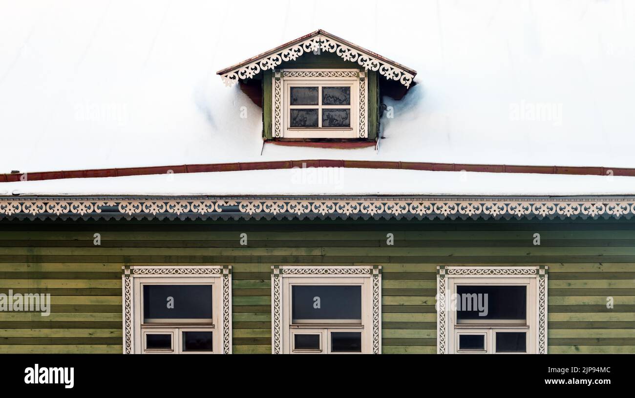 Gefrorenes Dachfenster im Dach mit Schnee bedeckt, altes Holzhaus außen Stockfoto