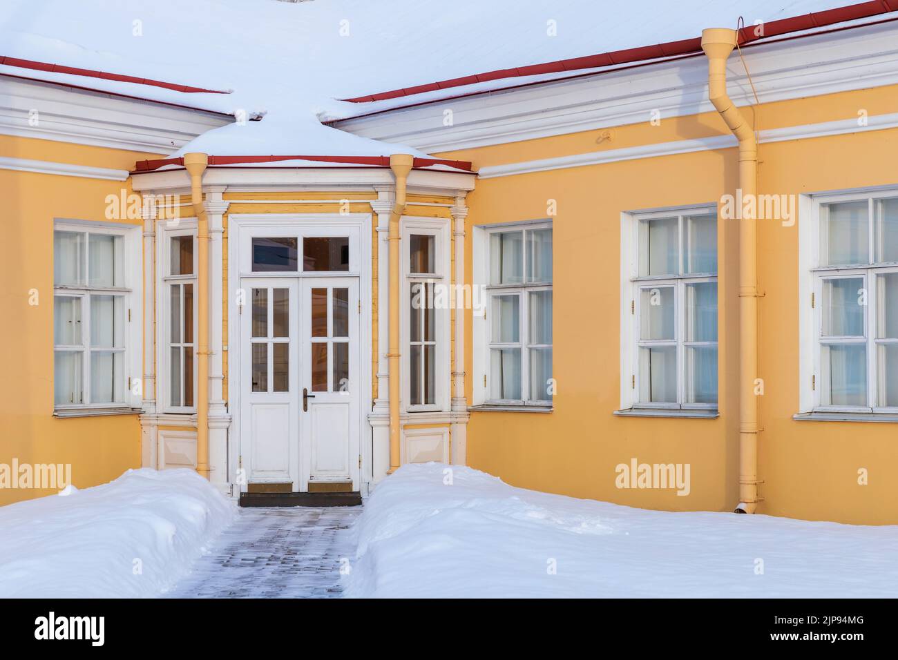 Eingang eines alten gelben Hauses an einem Wintertag Stockfoto