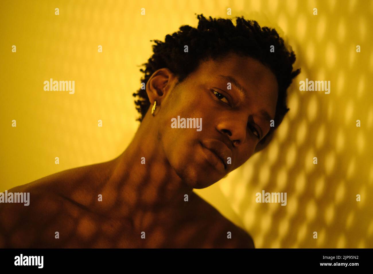 Porträt eines jungen afroamerikanischen Mannes auf gelbem Hintergrund mit Lichteffekten Stockfoto