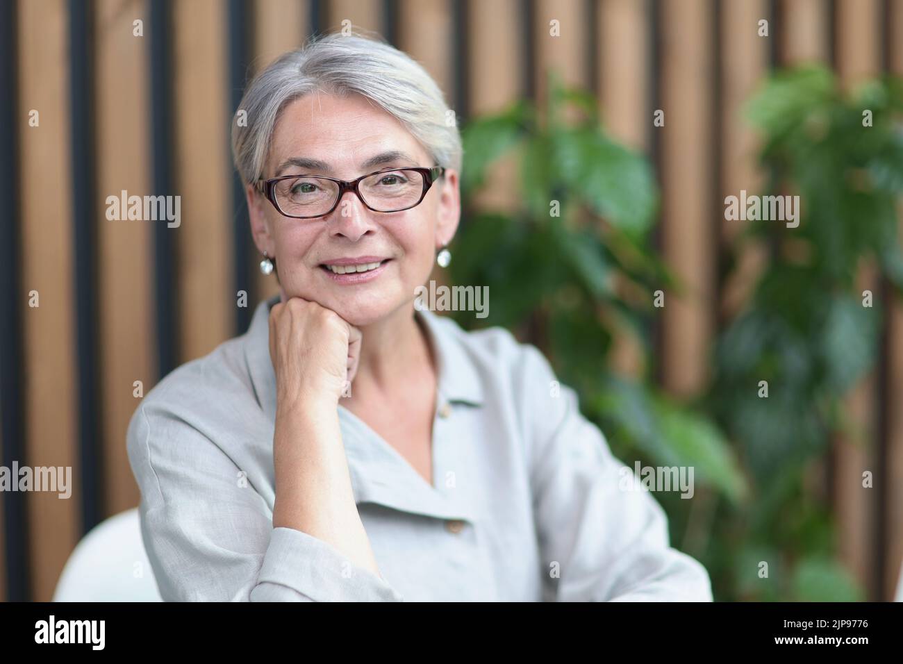 Lächelnde 60-jährige Geschäftsfrau, die im Büro einen Computer benutzt Stockfoto