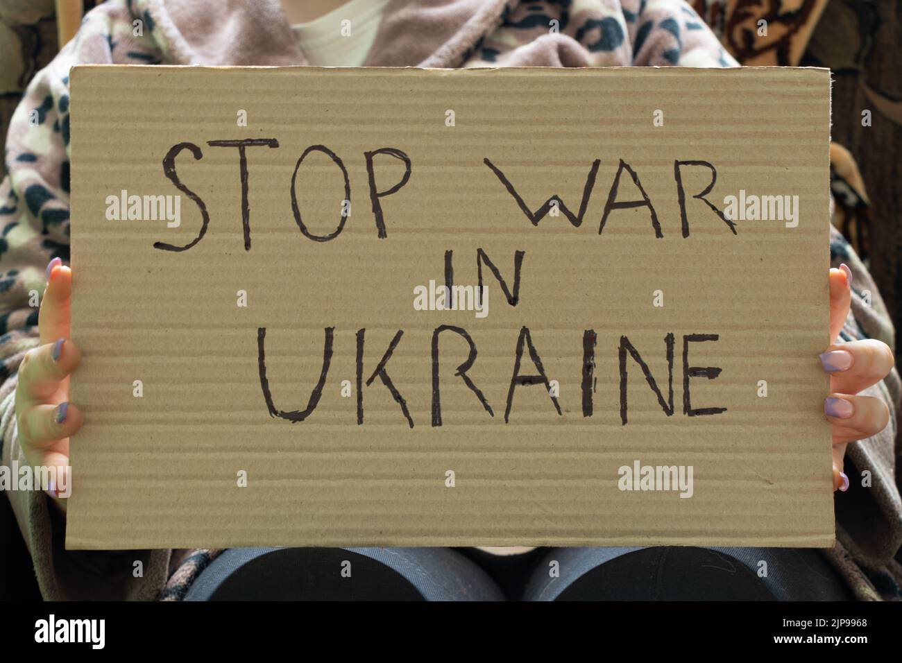 Stoppen Sie den Krieg in der Ukraine geschrieben auf einem Zeichen, dass eine Frau in ihren Händen hält von ihrem Haus in der Dnjepr, Protestaktion, Kriegsrecht in der Ukraine Stockfoto