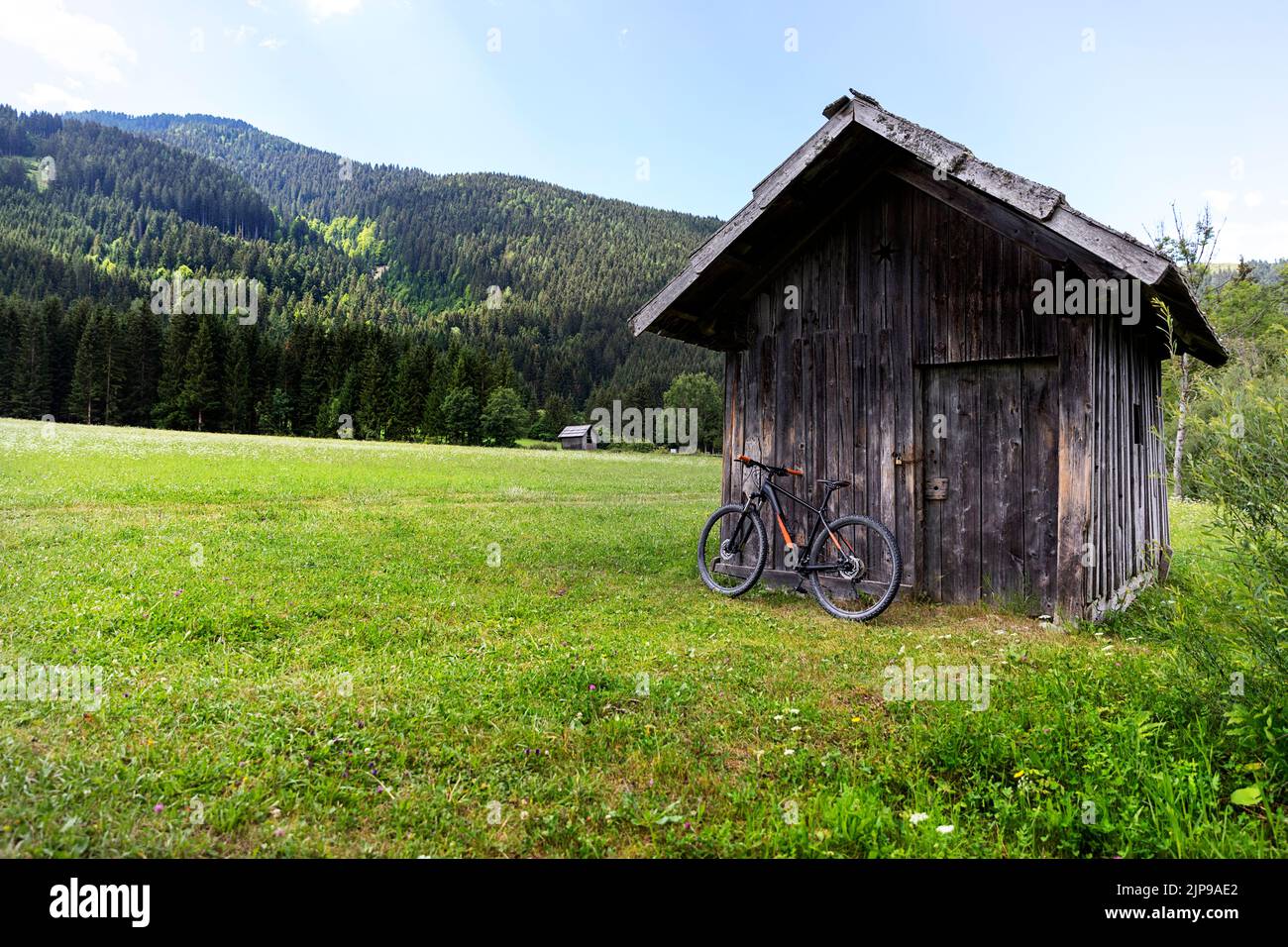 Mountainbike gegen die Wand einer traditionellen Holzhütte in der Nähe des Weissensees in Österreich Stockfoto