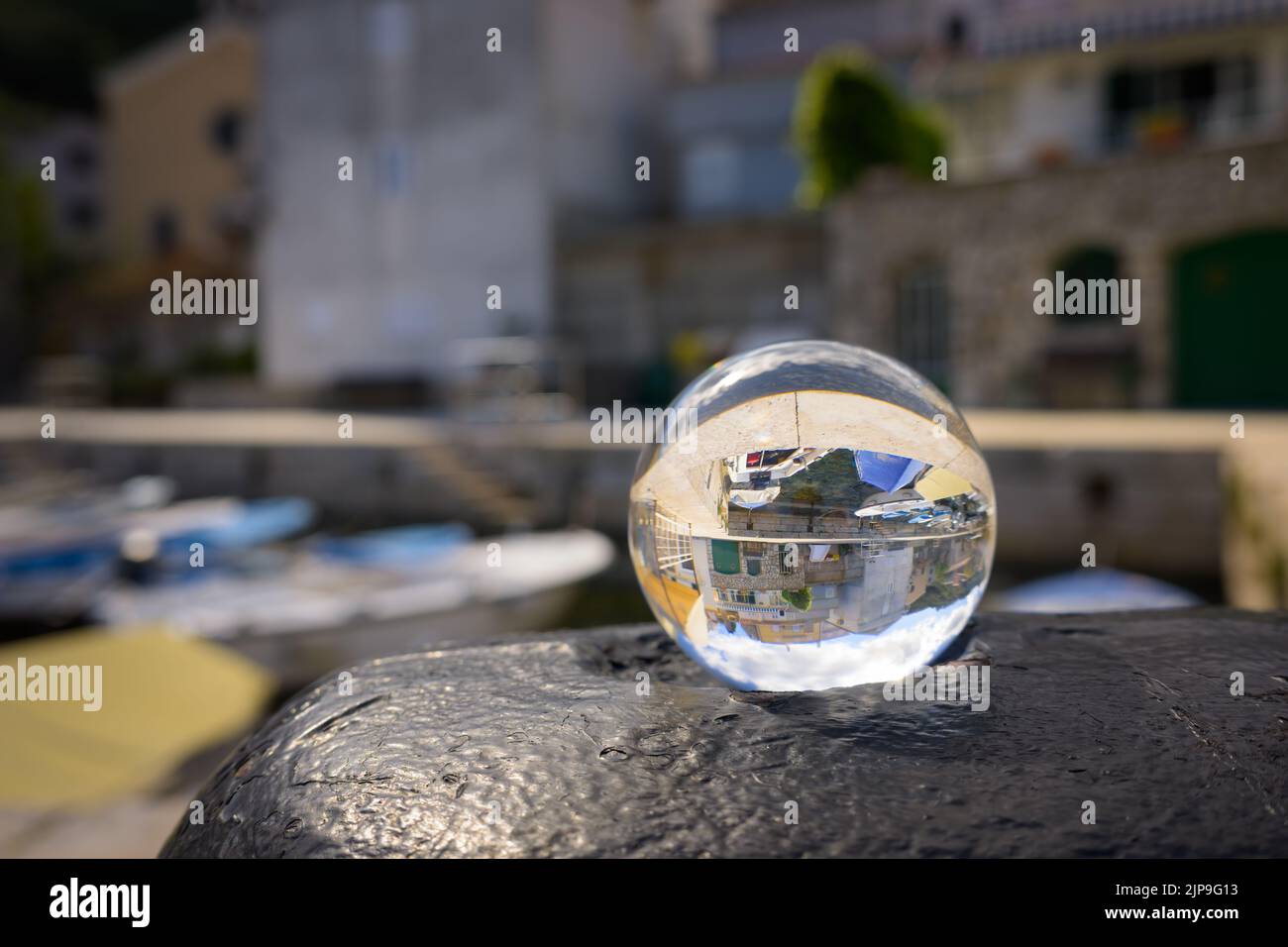 Glaskugel auf einem rostigen Poller, Hafen von Valun (Kroatien), sonniger Tag im Frühling Stockfoto