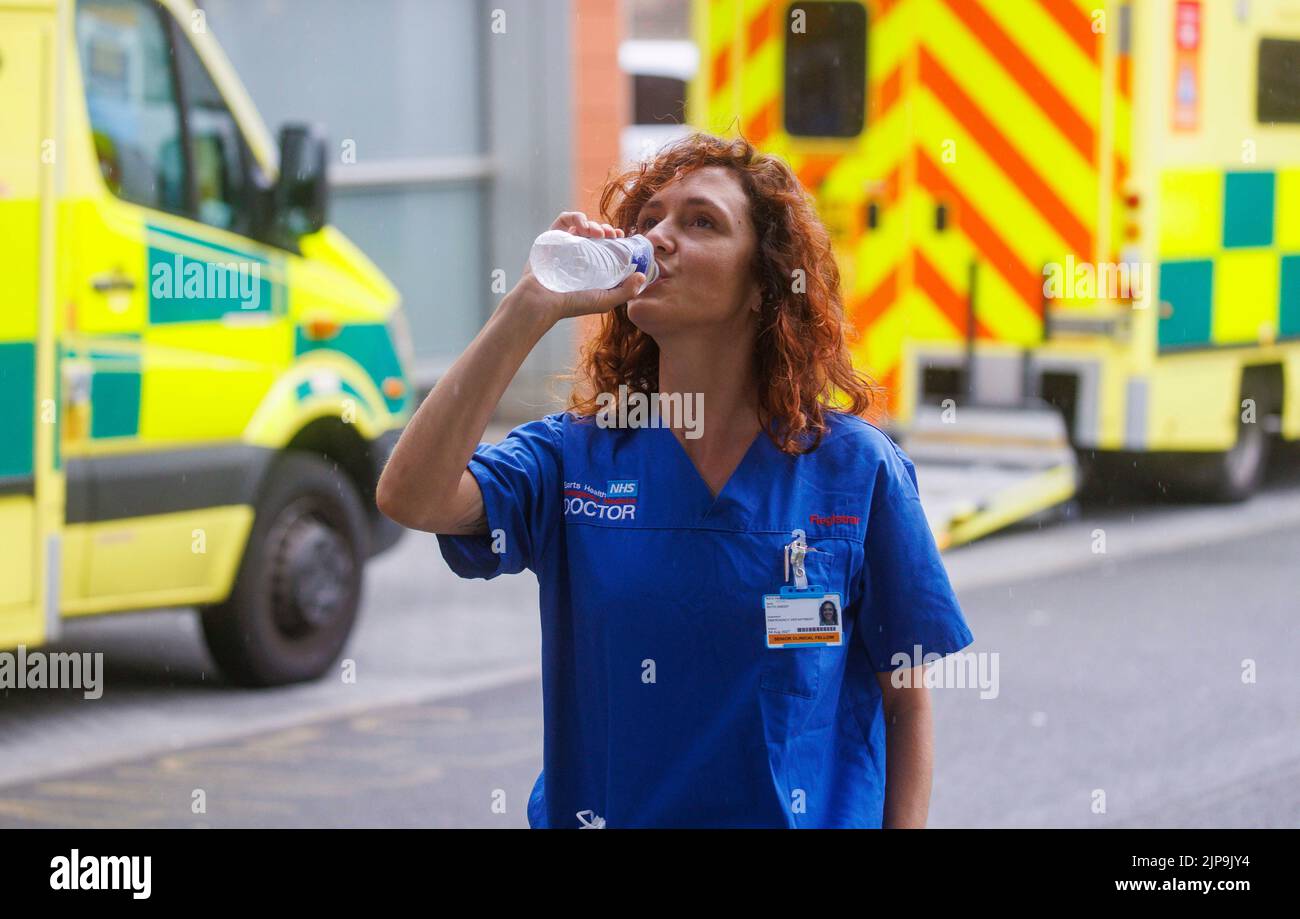 Ein Arzt des Gesundheitsdienstes kühlt während einer Pause in einem Londoner Krankenhaus mit einem Getränk Wasser ab. Der NHS steht unter Druck mit Unterfinanzierung und Arbeitsdruck. Stockfoto