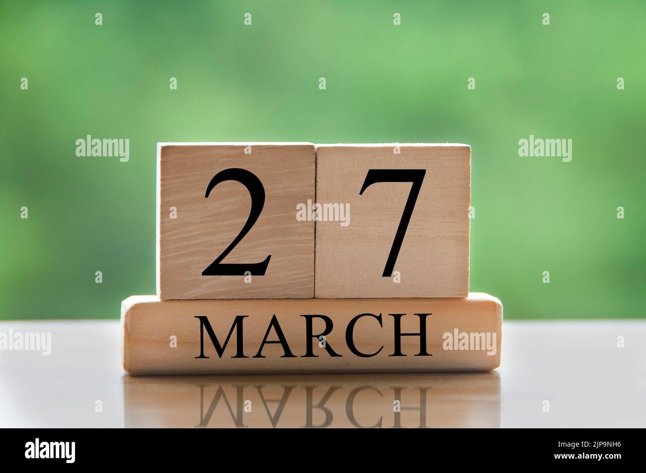 Kalenderdatentext März 27 auf Holzblöcken mit verschwommenem Parkhintergrund. Raum und Kalenderkonzept kopieren. Stockfoto