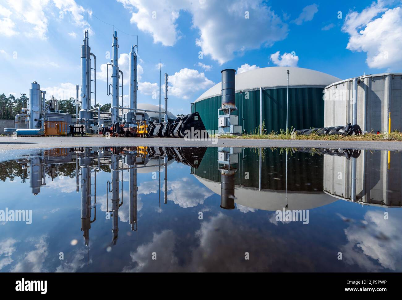 Torgelow, Deutschland. 16. August 2022. Die Biogasanlage in Torgelow spiegelt sich in einer Pfütze wider. Die Anlage versorgt 15.000 Einwohner der Stadt Torgelow. Die Anlage, die bisher aus sechs Gasspeichertanks des Unternehmens Mele Biogas bestand, wird bis Herbst 2023 ihre Kapazität verdoppeln. Hier soll nach Angaben des Landesverbands für Erneuerbare Energien Mecklenburg-Vorpommern ein Energievolumen von mehr als 100 Millionen Kilowattstunden pro Jahr produziert und auch in das Erdgasnetz eingespeist werden. Quelle: Jens Büttner/dpa/Alamy Live News Stockfoto
