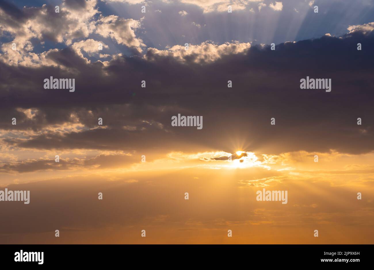 Der Sonnenuntergang über den Wolken. Warme Farben, leichte Sonneneruptionen. Stockfoto