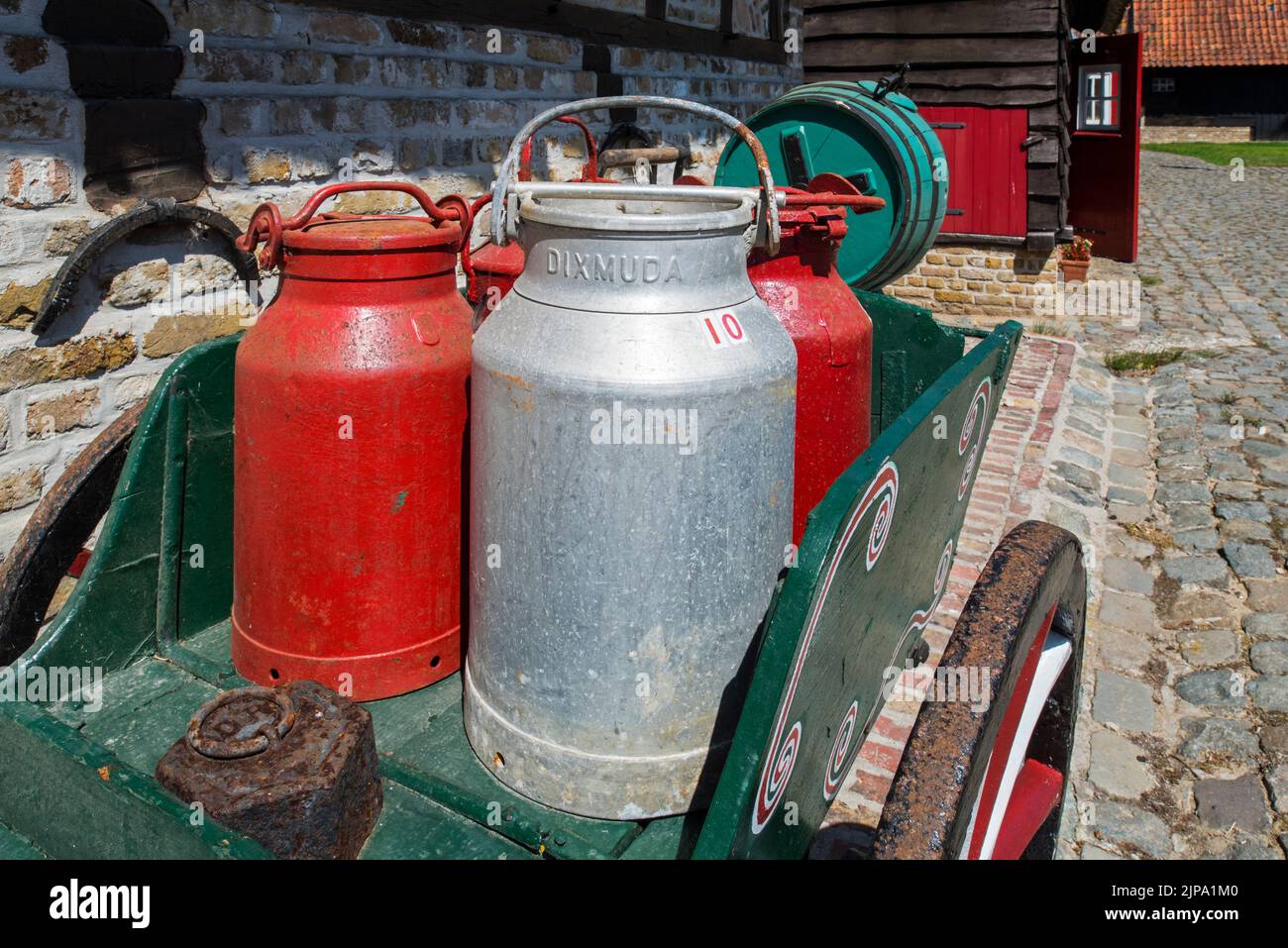 Antiker Handwagen, beladen mit alten Metall-Milchkrümmern / Milchdosen im Freilichtmuseum Bachten de Kupe im Sommer, Izenberge, Westflandern, Belgien Stockfoto