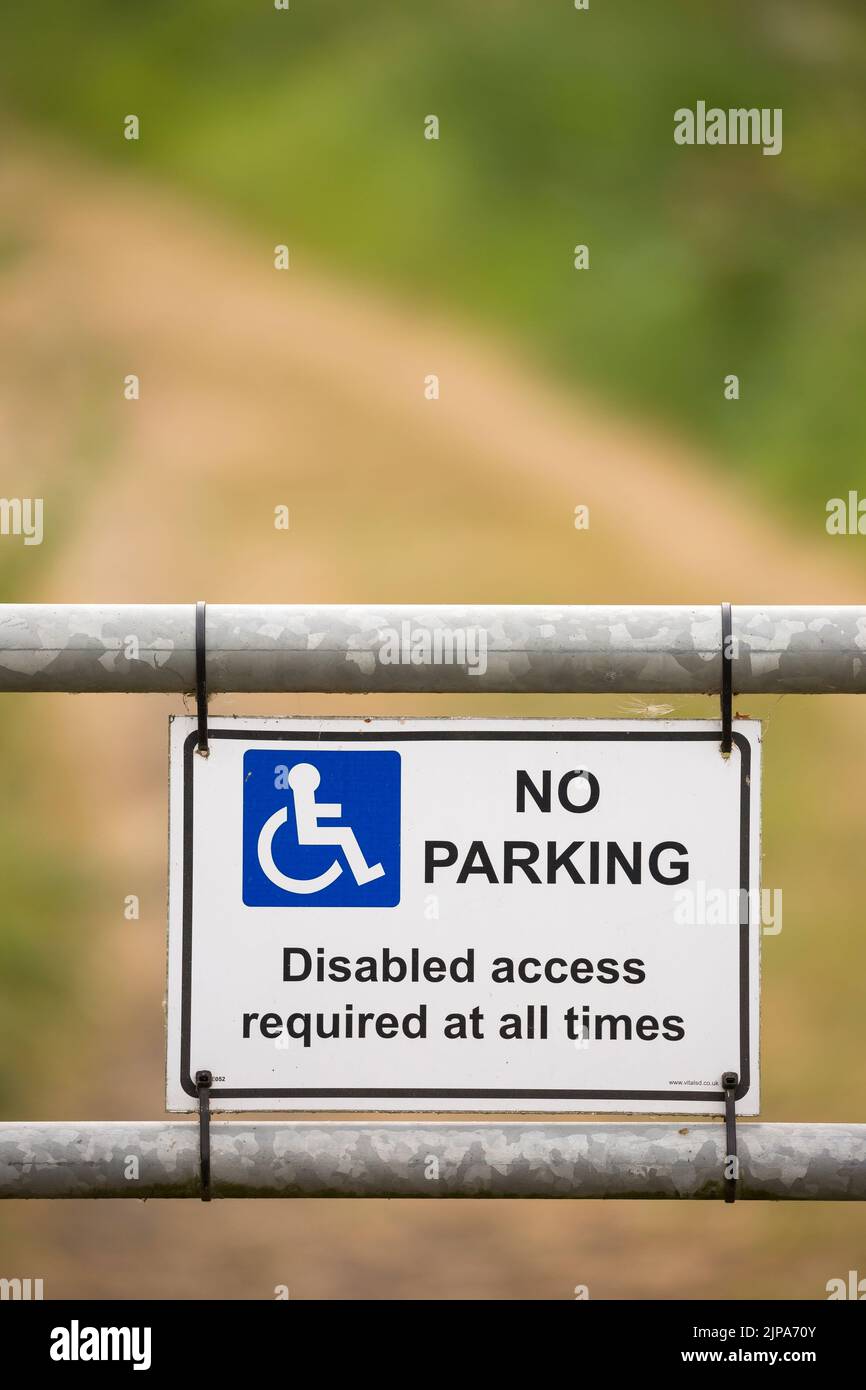 Nahaufnahme des blauen Schildes „No Parking“, das am Landstor angebracht ist, mit dem Hinweis, dass „Zugang für Behinderte jederzeit erforderlich ist“. Stockfoto
