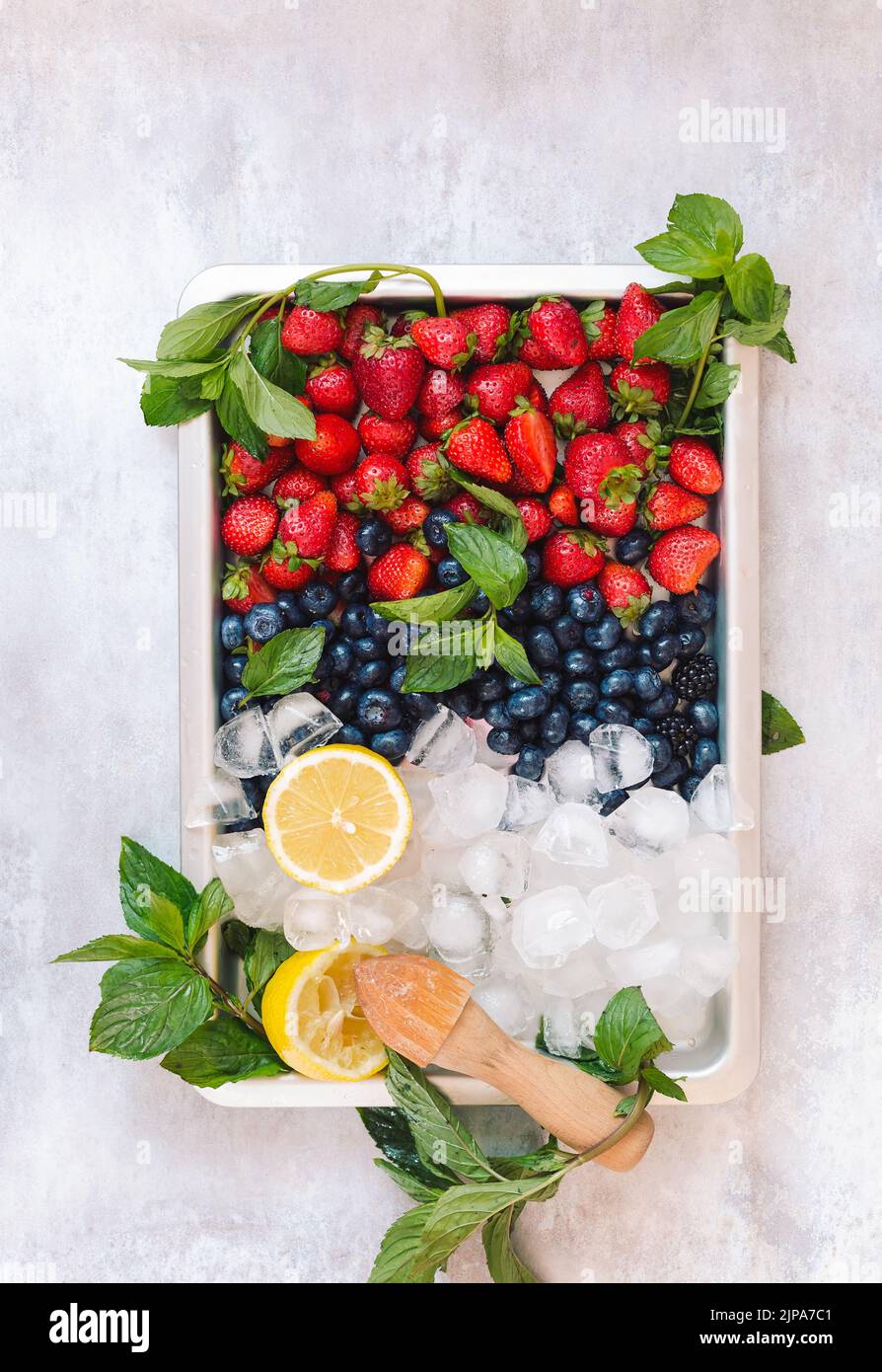 Beerenteller. Beerenfrüchte und Zitronen in einem Tablett mit Eiswürfeln. Stockfoto