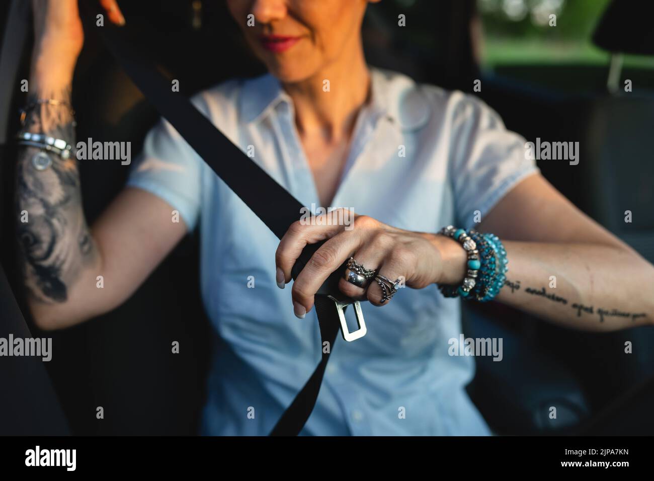 Eine kaukasische Autofahrerin sitzt im Auto, um den Sicherheitsgurt zu befestigen und das Sicherheitskonzept für das Fahren mit der Hand zu halten Stockfoto