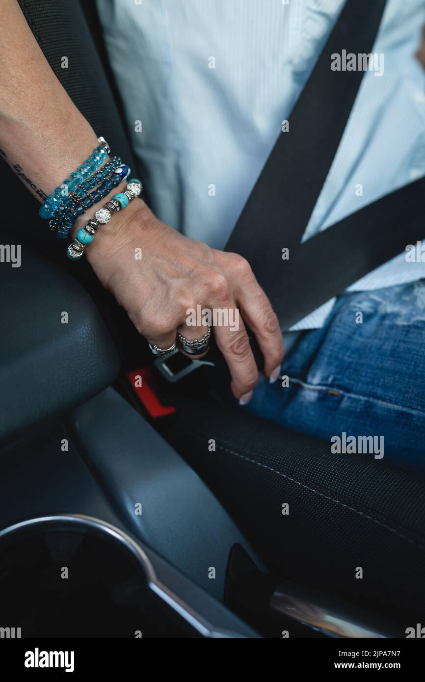 Eine kaukasische Autofahrerin sitzt im Auto, um den Sicherheitsgurt zu befestigen und das Sicherheitskonzept für das Fahren mit der Hand zu halten Stockfoto