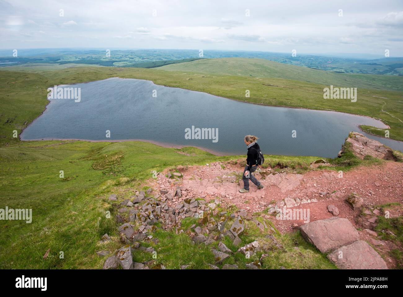 Eine Person in einem kleinen Rucksack geht hinunter zu einem See in den Brecon Beacons in Wales, Großbritannien Stockfoto