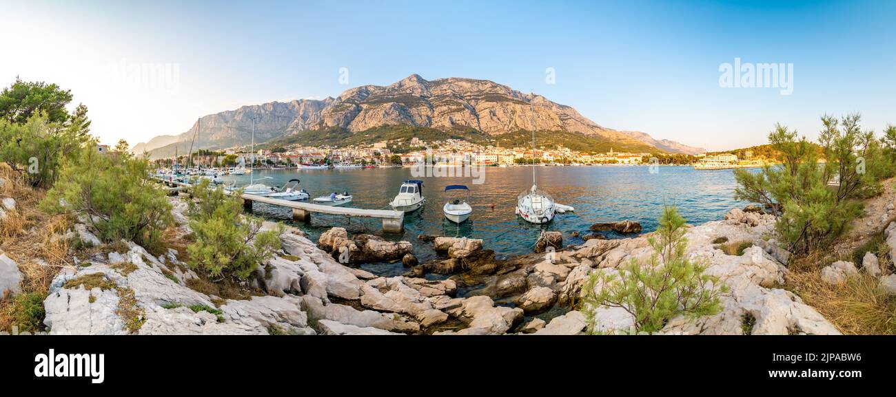 Panoramablick auf die Stadt Makarska, Kroatien während des Sonnenuntergangs. Blick mit kleinen Booten und Biokovo Bergen im Hintergrund. Sommerwetter, weich, warm, CO Stockfoto