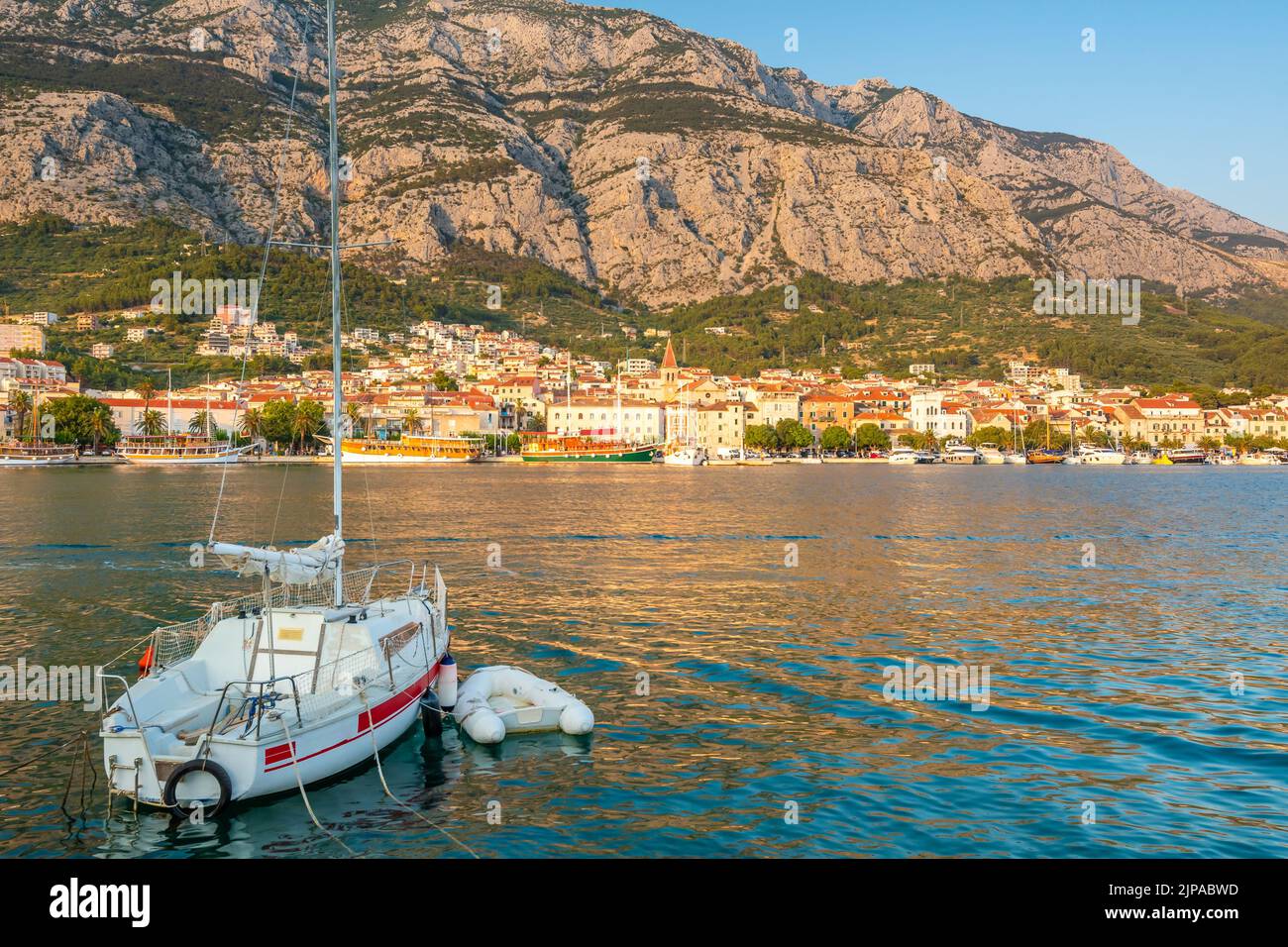 Panoramablick auf die Stadt Makarska, Kroatien während des Sonnenuntergangs. Blick mit kleinen Booten und Biokovo Bergen im Hintergrund. Sommerwetter, weich, warm, CO Stockfoto