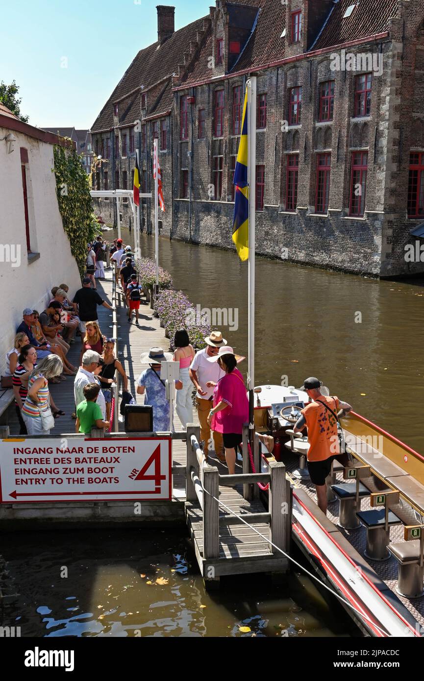 Brügge, Belgien - 2022. August: Menschen, die nach einer Fahrt durch das Kanalsystem der Stadt aus dem Motorboot aussteigen Stockfoto