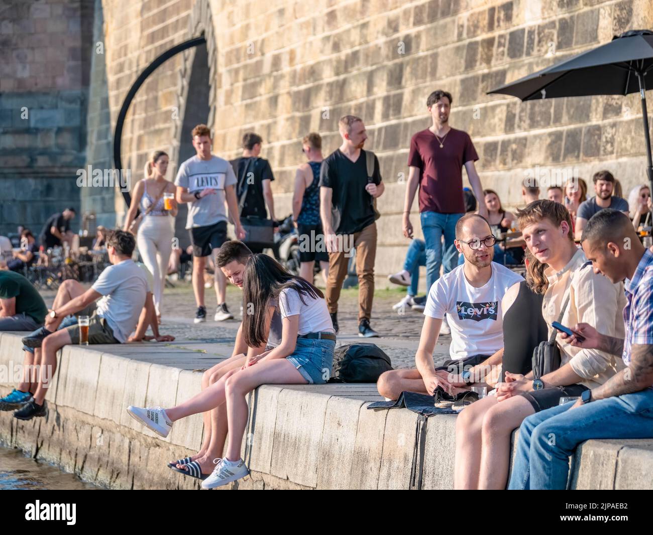 Prag, Tschechische Republik - 2022. Juni: Touristen und Einheimische sitzen und trinken ein Bier auf der Naplavka entlang der Moldau in Prag Stockfoto