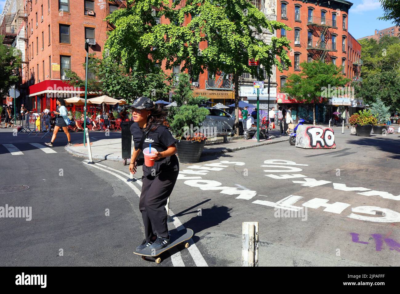Eine Skateboarderin mit einer quart-großen Wassermelone-Slushie fährt an einer NYC Greenstreet in Manhattans „Dimes Square“ Chinatown/Lower East Side vorbei Stockfoto