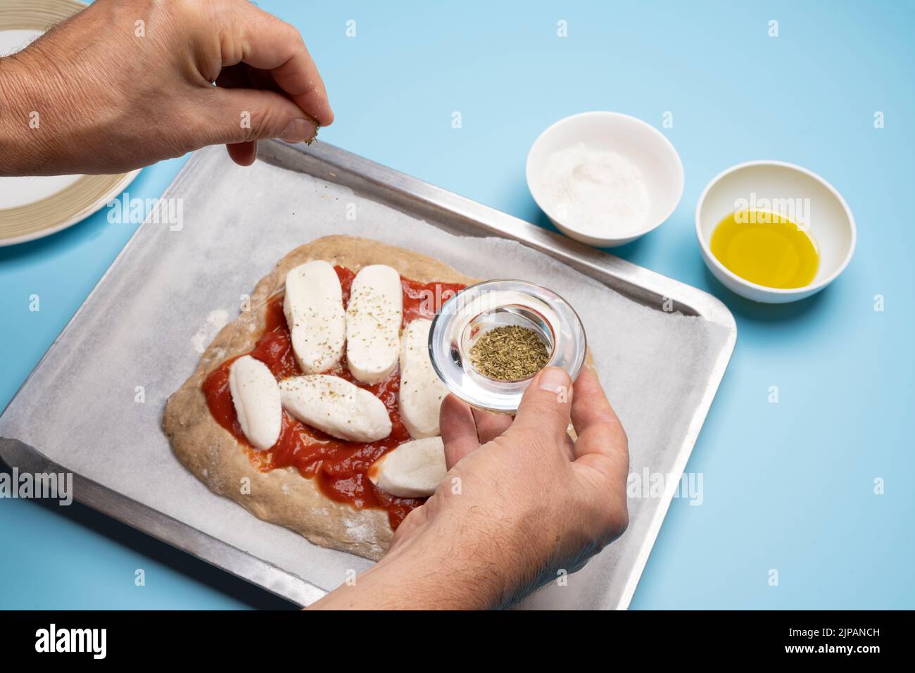 Pizza in der heimischen Küche zubereiten (Schritte 1 bis 14). Schritt 10: Fügen Sie eine Prise Oregano hinzu. Stockfoto