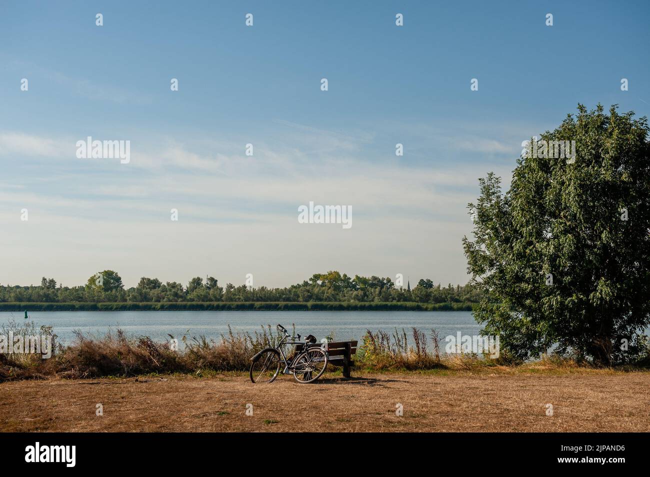 Ein Fahrrad gesehen geparkt neben einem Fluss und einem sehr trockenen Feld. Dieses Wochenende war offiziell der wärmste August 14. seit Beginn der Temperaturmessungen im Jahr 1901. Damit ist es der fünfte tropische Tag in Folge der Hitzewelle, die sich im Gange befindet. Stockfoto