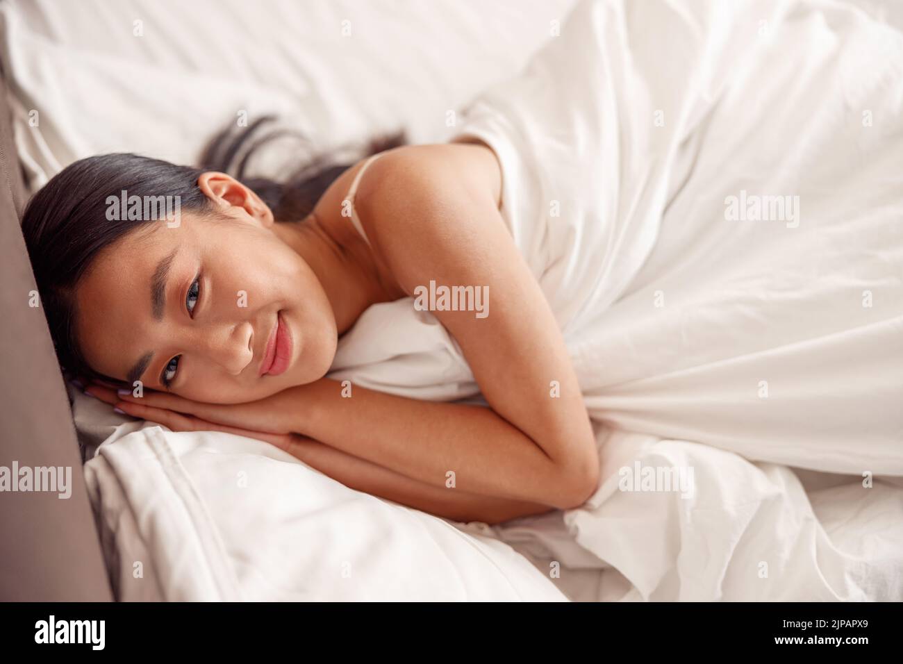Asiatische junge Frau, die zu Hause im Bett ruht Stockfoto