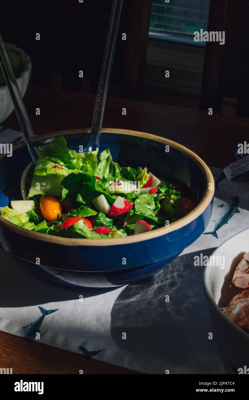 Salat mit Tomaten, Rettich in blauer Schüssel Stockfoto