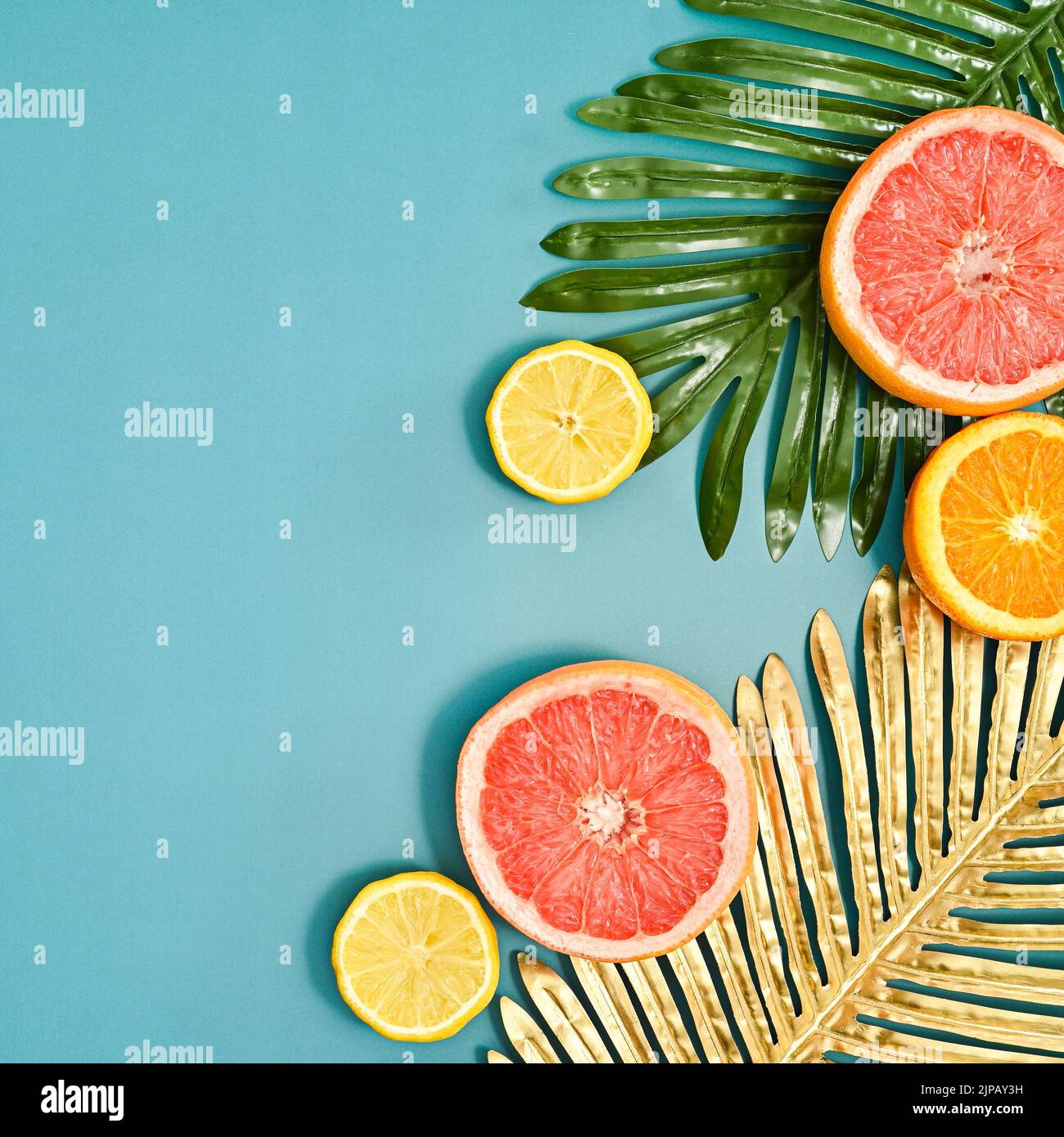 Sommerfrüchte Arrangement mit Palmblättern und Zitrusfrüchten auf blauem Backgorund. Flacher, laygerer Kopierplatz Stockfoto