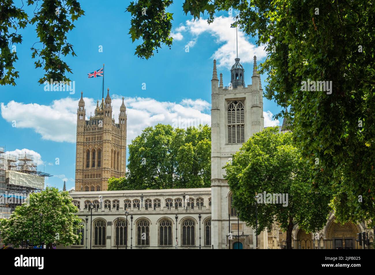 London, Großbritannien - 4. Juli 2022: Parliament Square Gardens. St. Margaret's Church und Victoria TOWERIn zurück unter blauer Wolkenlandschaft. Grünes Laub ringsum. Stockfoto