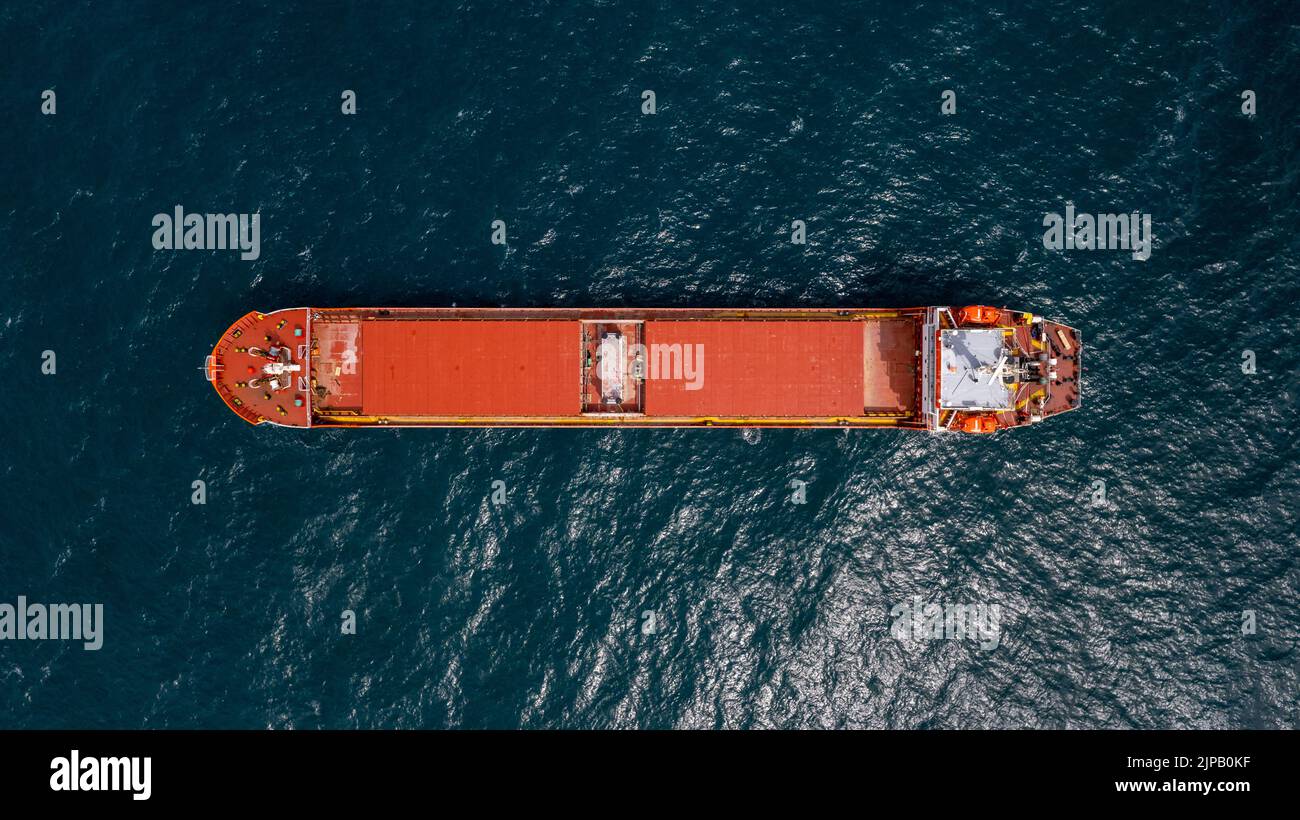Unbeladenes rotes Frachtschiff, das in ruhigem Wasser verankert ist. Stockfoto