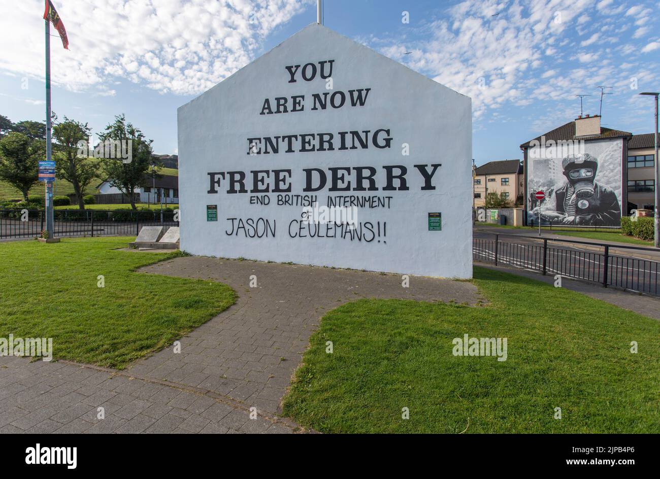 Schild in Free Derry mit Wandbild von Bogside Artists an der Seite des Hauses in Derry, Nordirland. Stockfoto