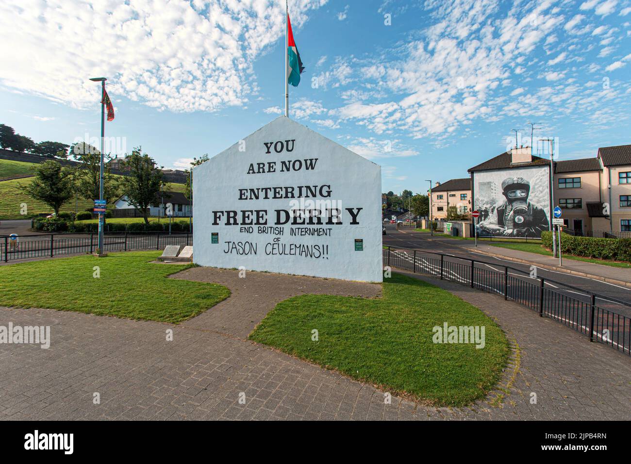 Schild in Free Derry mit Wandbild von Bogside Artists an der Seite des Hauses in Derry, Nordirland. Stockfoto