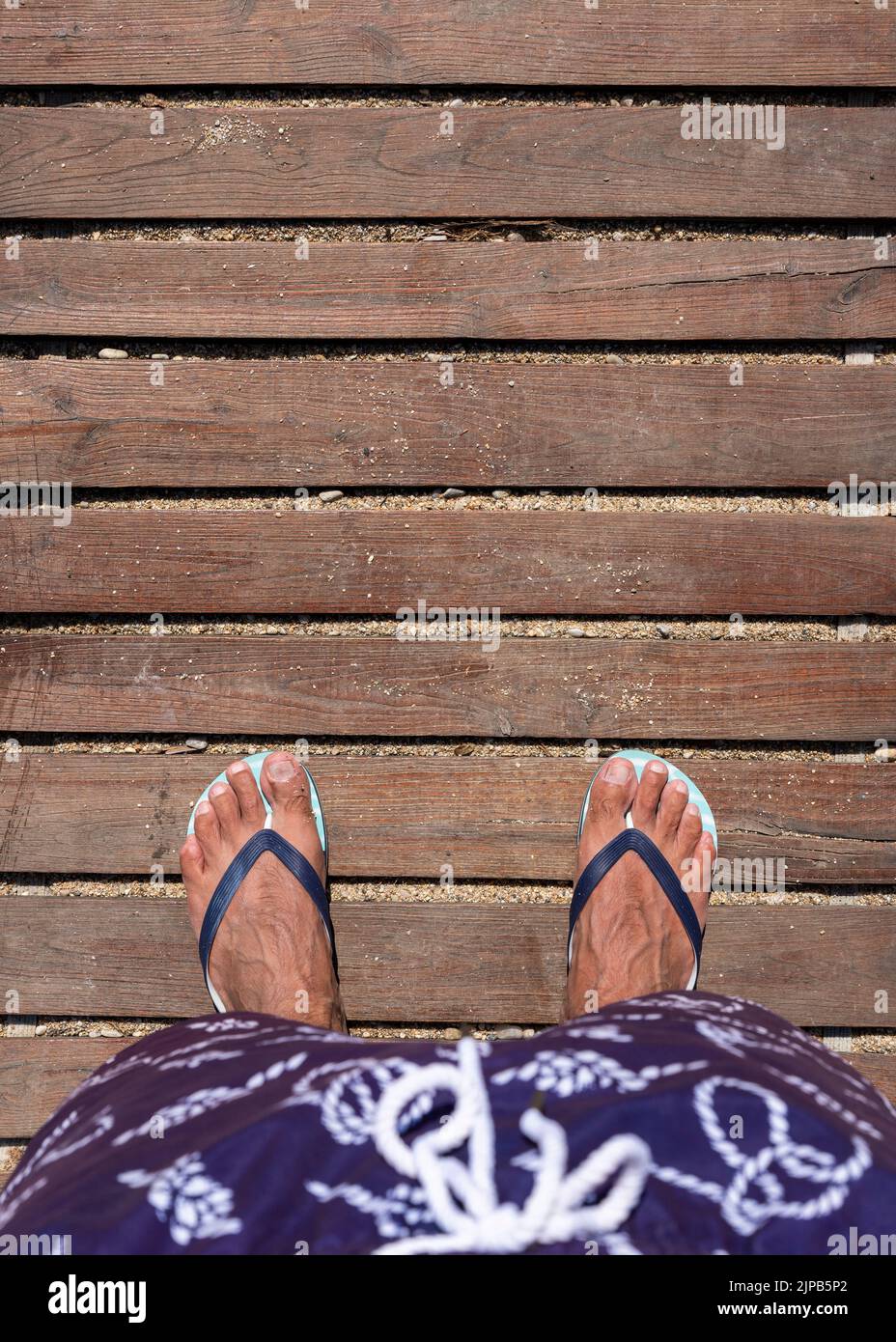 Füße in Flip-Flops auf der Holzpromenade. Draufsicht. Flach liegend. Leeres Leerzeichen für Text oder Logo Stockfoto