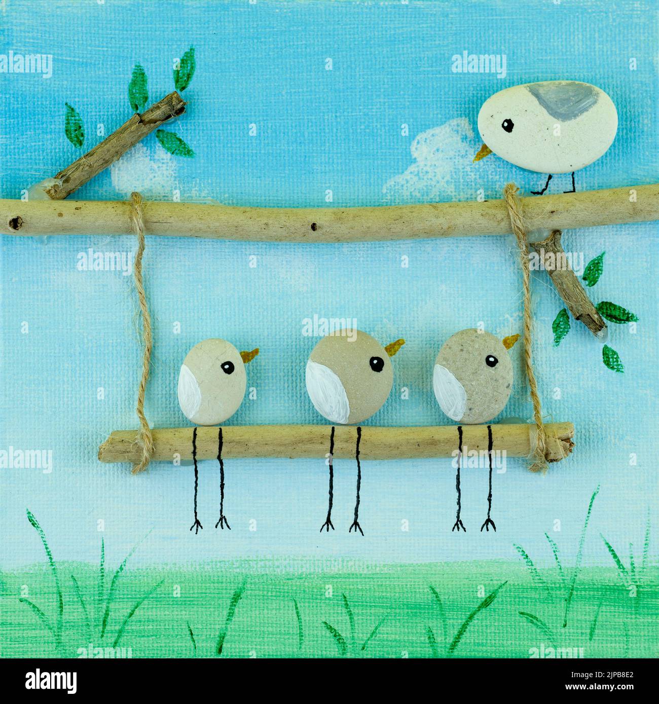 Handgemachtes kreatives Konzept mit Vögeln aus Stein und bemalter Leinwand mit farbenfroher Wiese Stockfoto
