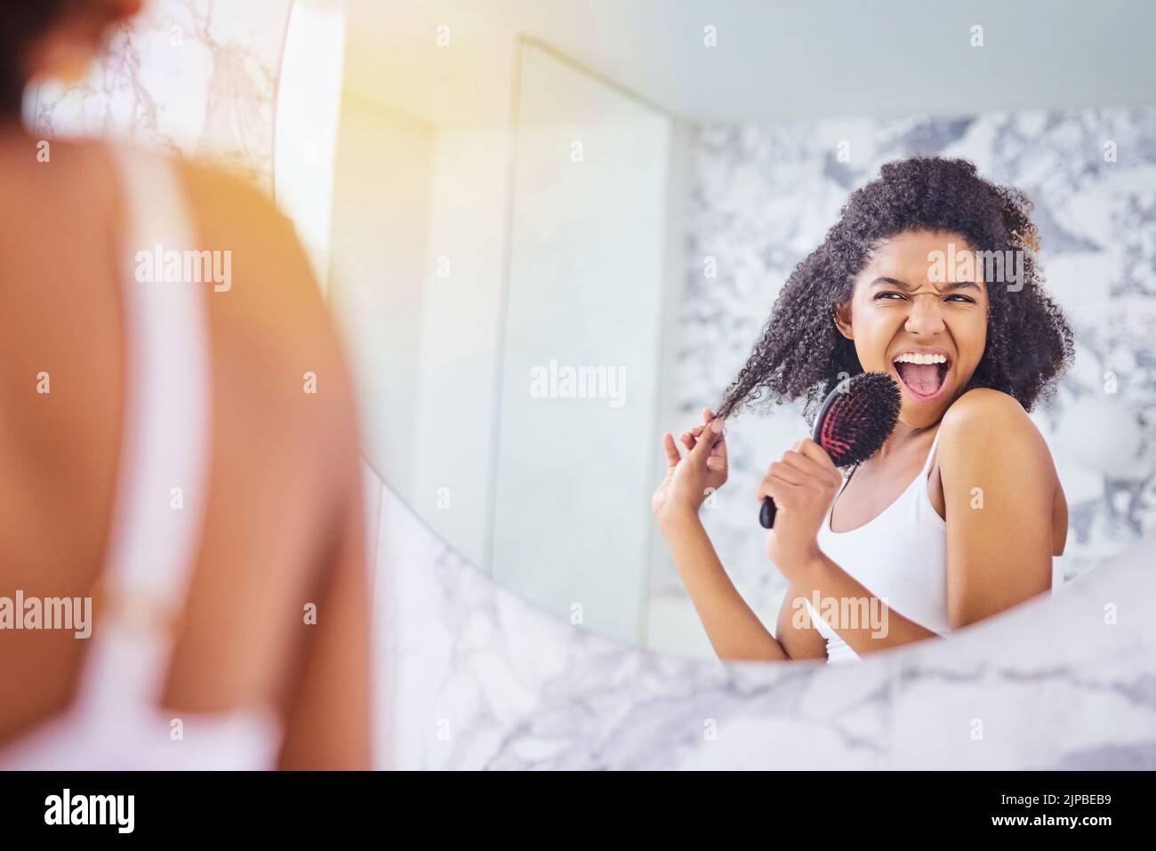 Fühlen Sie sich fabelhaft, sehen Sie fabelhaft aus. Eine attraktive junge Frau singt beim Haarbürsten im Badezimmer zu Hause. Stockfoto