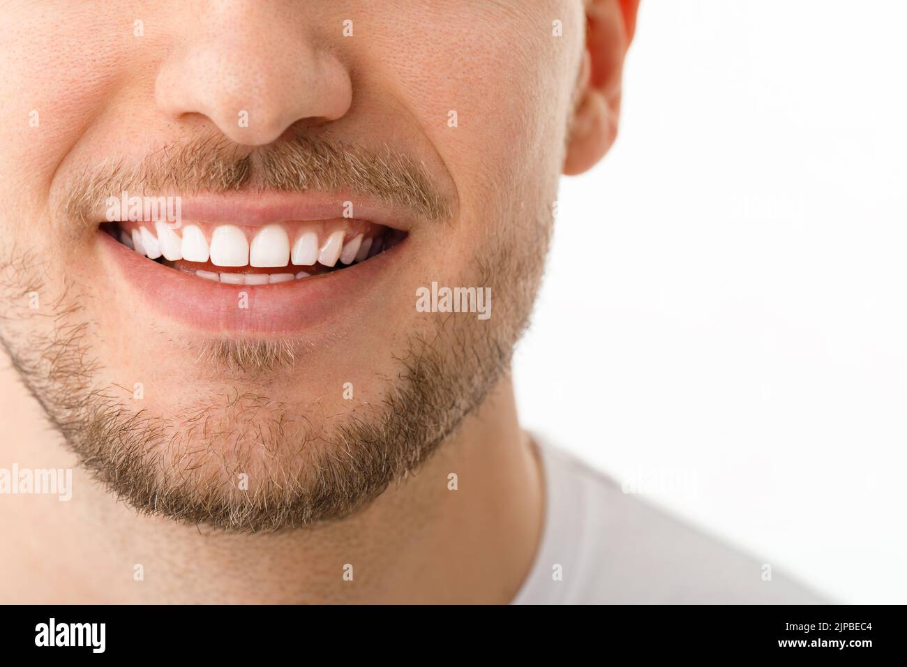 Ein Mann lächelt. Ein Lächeln mit weißen Zähnen. Nahaufnahme des Bildes. Weißer Hintergrund mit Copyspace. Stockfoto