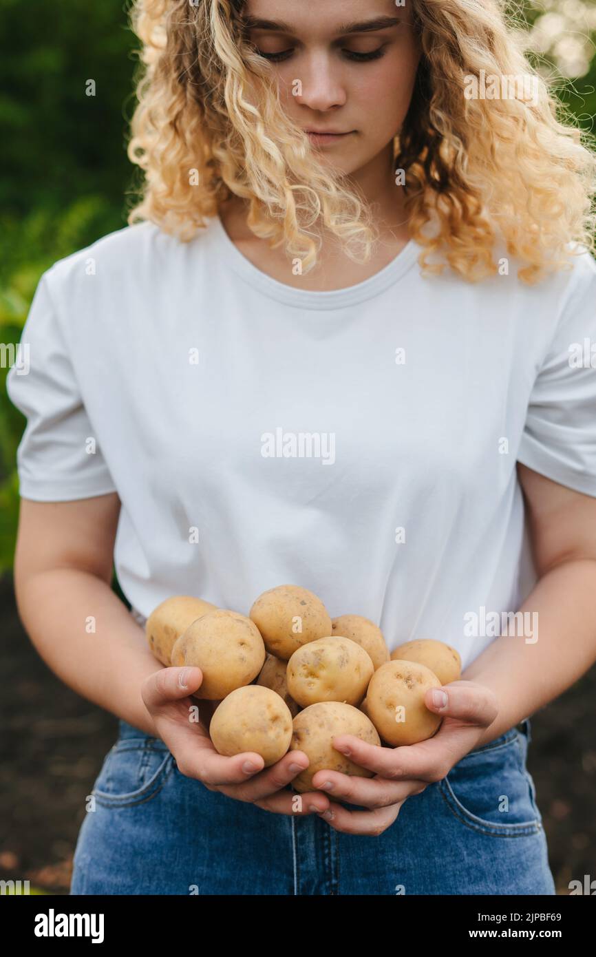 Das kalkige Mädchen hält Kartoffeln in den Händen, ein Zeichen für eine ...