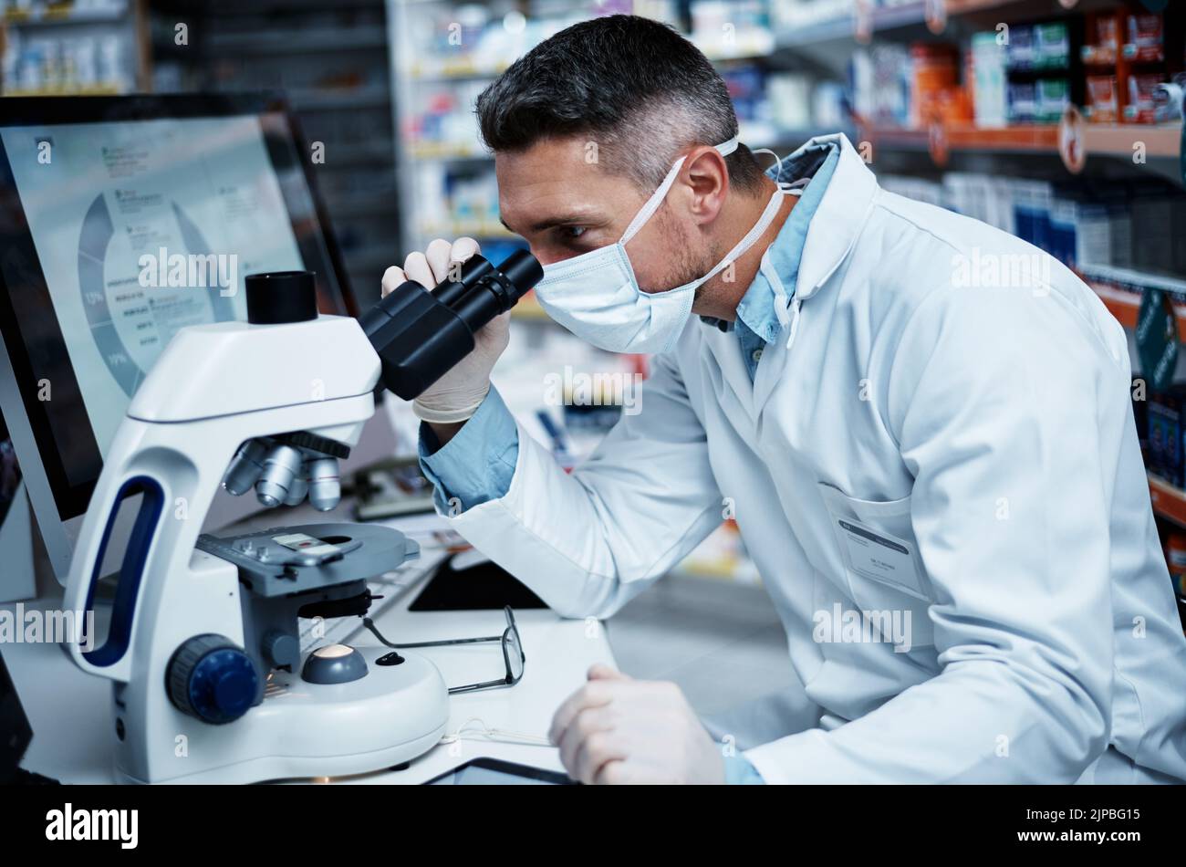 Er entwickelt effektive neue Medikamente. Ein reifer Mann, der ein Mikroskop benutzt, während er pharmazeutische Forschung betreibt. Stockfoto